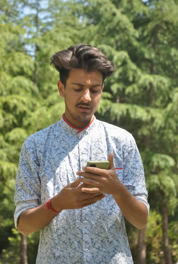 Portrait of a Indian handsome young guy standing outside with using mobile phone Portrait of a Indian handsome young guy standing outside with using mobile phone